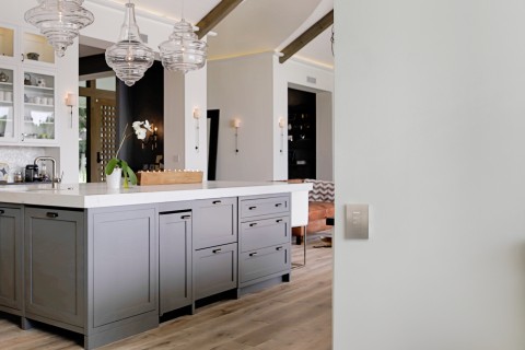 A home with beautiful pendant lights above a countertop and a Palladiom keypad on the wall.