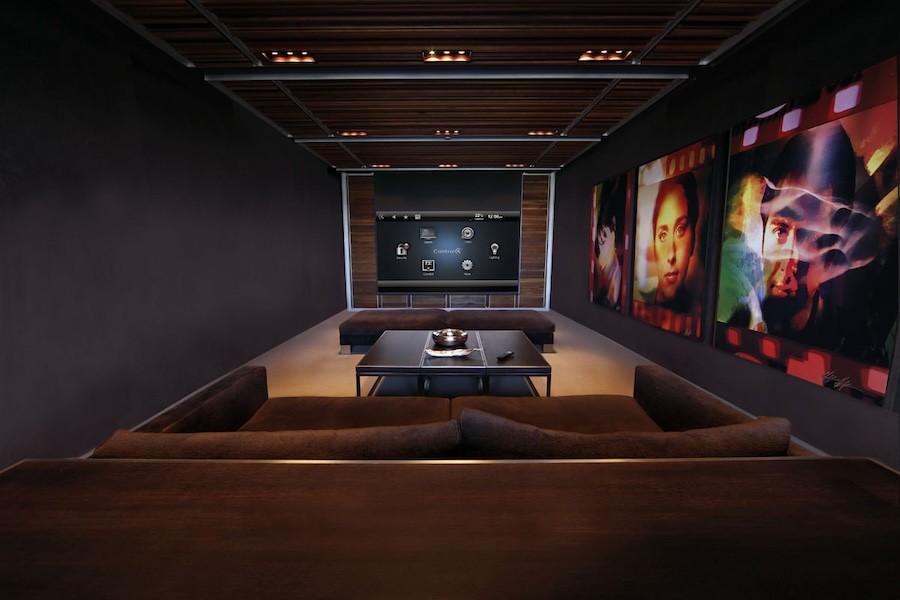 A home theater with a large loveseat, a coffee table, and film-style graphics on the wall.