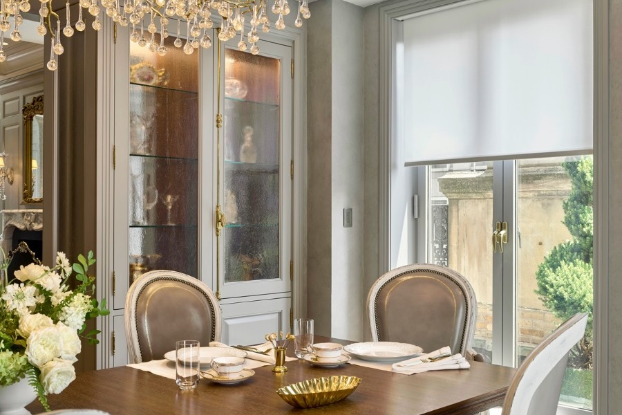 Elegant dining room featuring a chandelier, a table, and motorized shades.