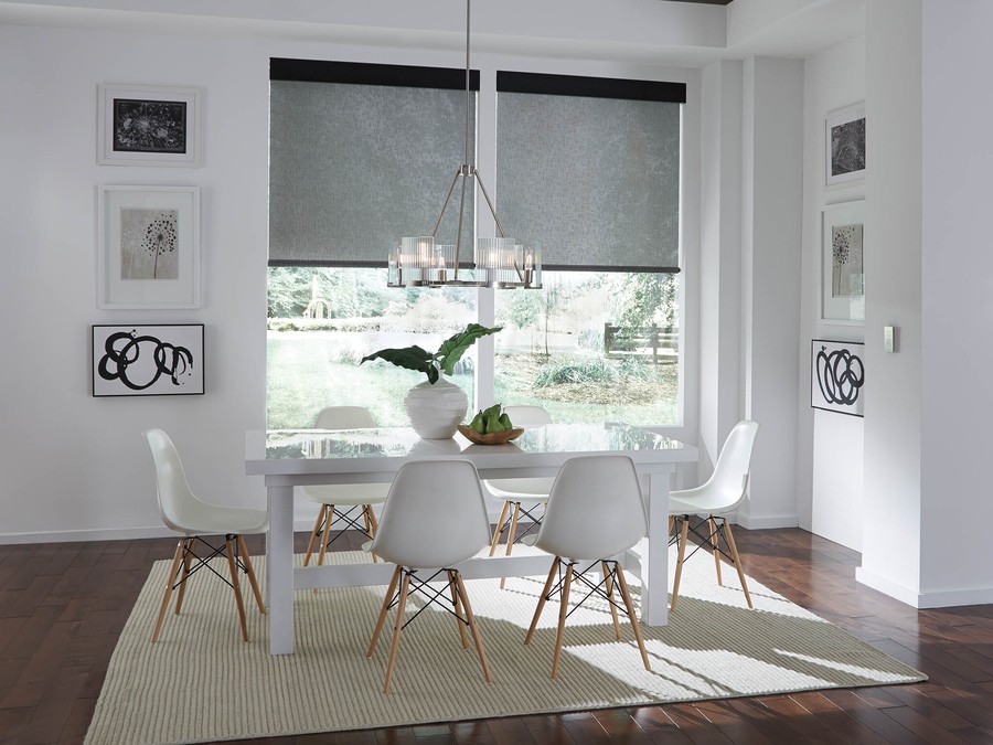 A dining room with Lutron motorized shades halfway drawn over windows, letting natural light peer through.