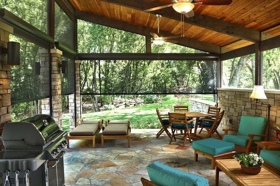 An outdoor porch area during the day with motorized shades and outdoor furniture.