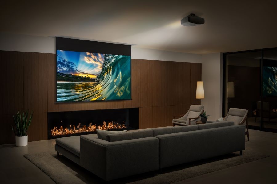 A living room with a Sony short throw projector displaying an image of a wave on a movie screen above a fireplace.