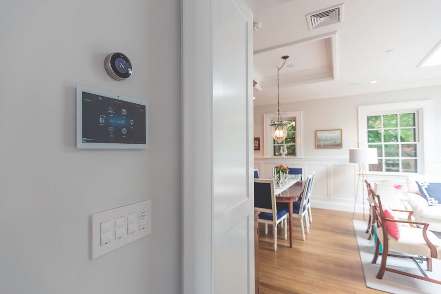 A tablet and smart thermostat mounted on a wall displaying a smart home interface. 